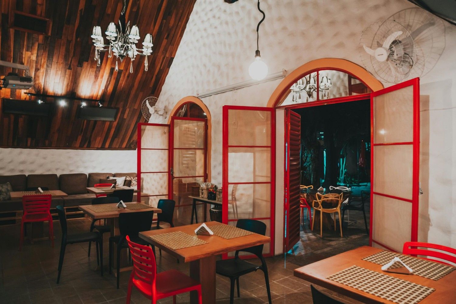 Intérieur de restaurant chaleureux et accueillant, avec des détails en bois et des touches de rouge pour une ambiance cosy.